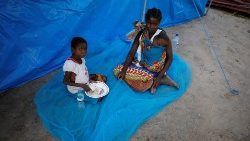 a-woman-and-her-children-sit-beside-a-tent-in-1553796270135.JPG