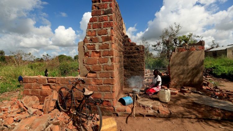 A woman cooks at her damaged house in the aftermath of Cyclone Idai, outside the village of Cheia near Beira, Mozambique