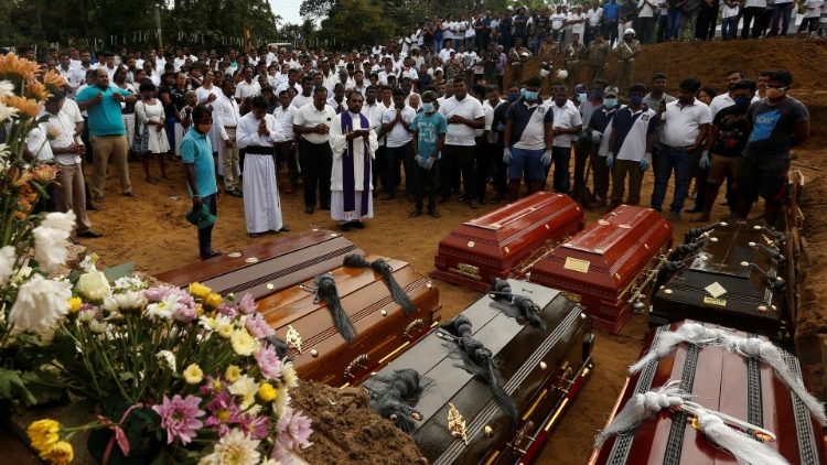 People participate in a mass funeral in Negombo
