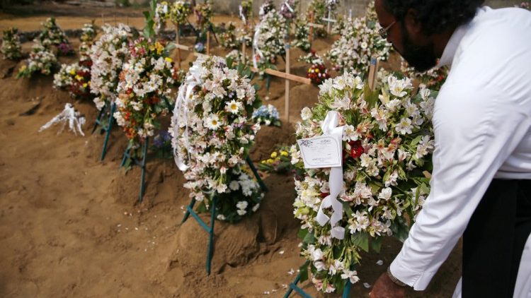 A priest arranges flowers at the site of a mass burial in Negombo, Sri Lanka