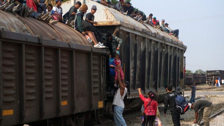 Central American migrants climb on a train known as "The Beast", continuing their journey towards the United States, in Ixtepec