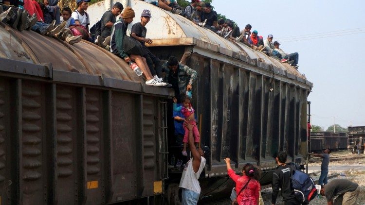 Central American migrants climb on a train known as "The Beast", continuing their journey towards the United States, in Ixtepec