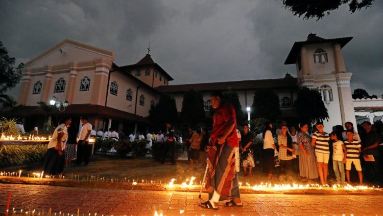 A survivor and a devotee arrives to light candles at the St. Sebastian church during the first-month remembrance service in Negombo