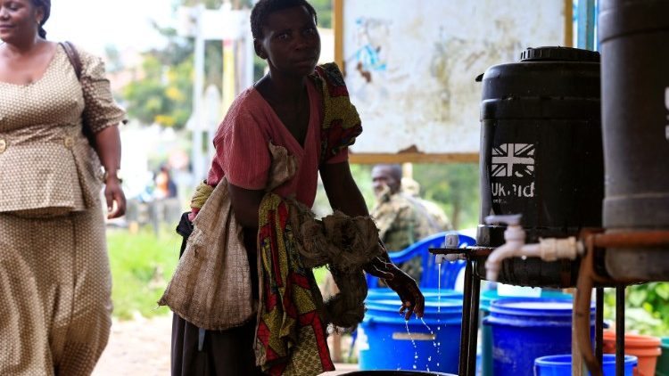 Una donna si lava le mani al confine tra Uganda e Repubblica Democratica del Congo