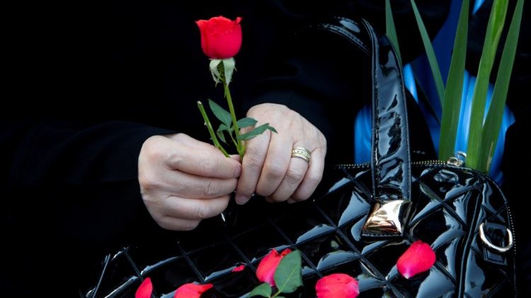 An Iranian woman holds a red flower as she attends a ceremony to bury remains of 150 "martyrs" from 1980-88 Iran-Iraq war in Tehran