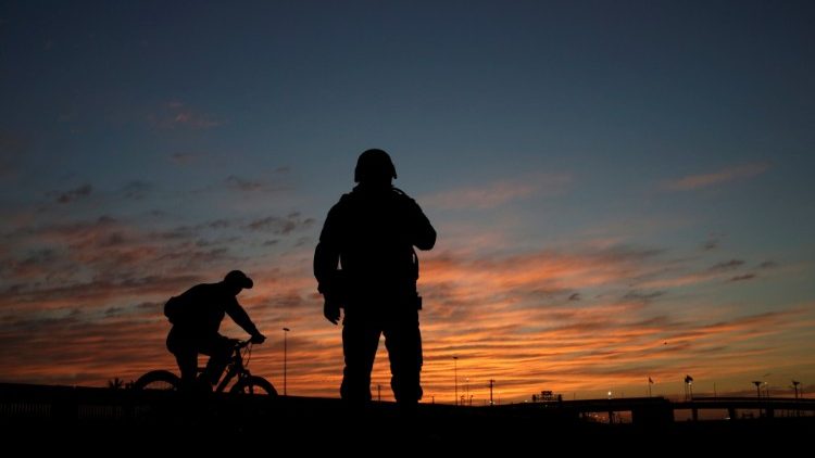 A man rides a bicycle next to a Mexican National Guard soldier near the US border