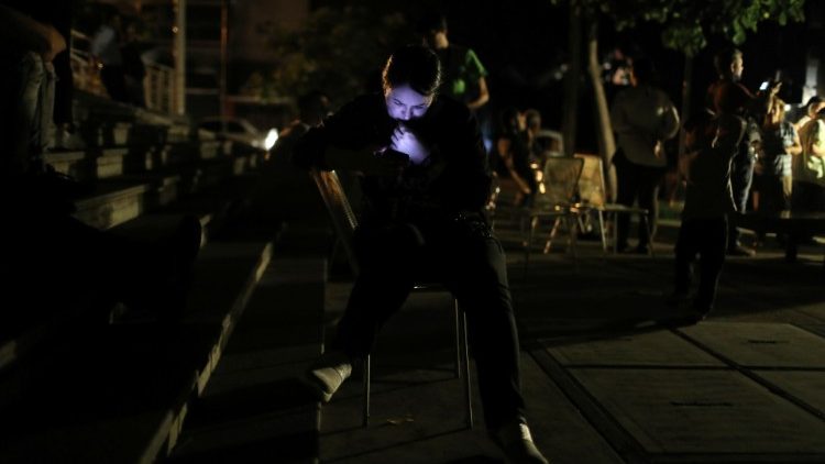A Venezuelan woman uses her cell phone during a blackout in Caracas
