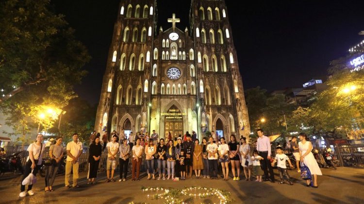 Residents light candles to pray for 39 people found dead in the back of a truck near London, in front of Hanoi Cathedral in Hanoi