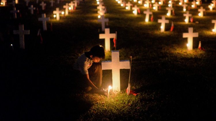 A boy scout lights candles during a tribute for departed soldiers on All Saints Day at a cemetery in Taguig City