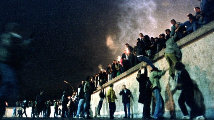 Des Allemands de l'Est escaladent le mur de Berlin, le 9 novembre 1989. 