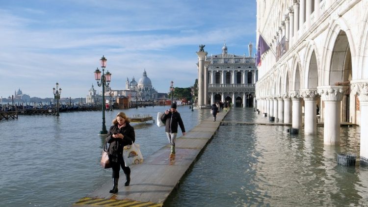 People walk in the flooded St. Mark's Square during high tide in Venice