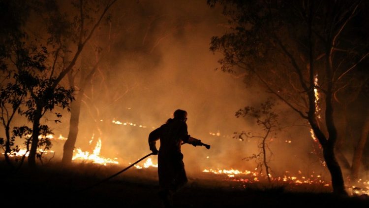 A firefighter works to extinguish flames after a bushfire burnt through the area in Bredbo