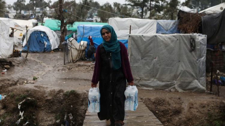 ग्रीस के लेस्बो स्थित शरणार्थी शिविर के बाहर पानी ले जाती एक महिला, तस्वीर 06.02.2020