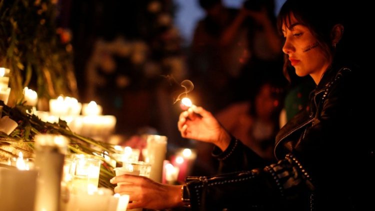 A woman holds a candle as she protests against gender violence and femicides at Angel de la Independencia monument in Mexico City