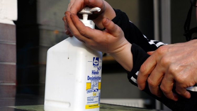 Criança usa desinfetante nas mãos na entrada de uma sorveteria em Berlim
