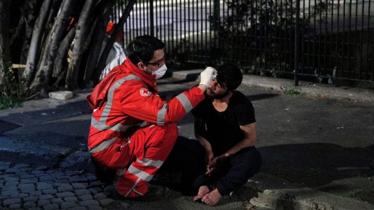 A homeless person is treated by a Red Cross worker in Rome