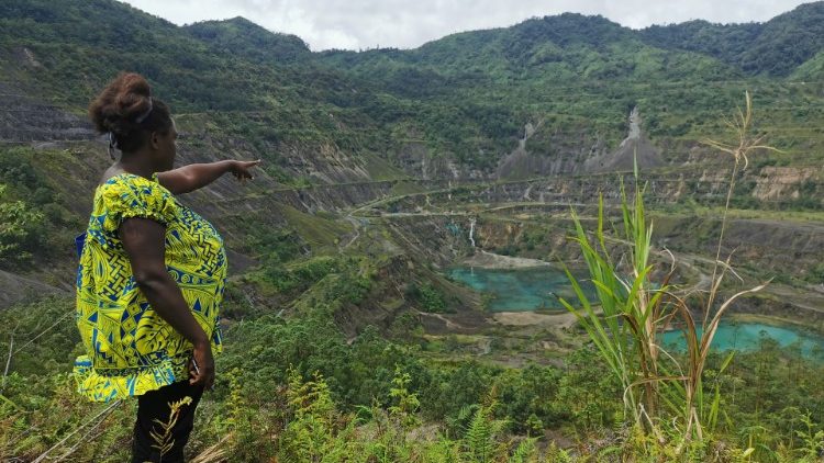 A local woman points towards the remains of Rio Tinto's Panguna mine, which locals say have contaminated local waterways, in Bougainville