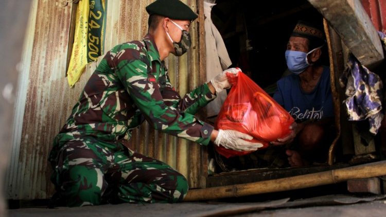 Indonesian soldier wearing a protective mask and gloves distributes free food to locals amid the spread of coronavirus disease (COVID-19) outbreak, in Makassar