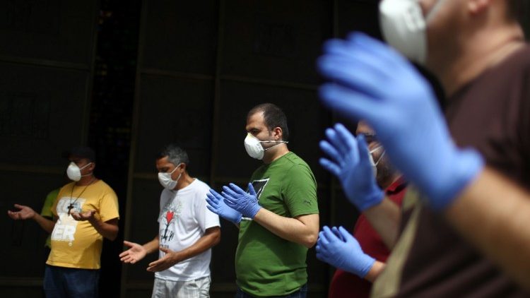 Fe y Acción contra la pandemia: voluntarios en Brasil rezan antes de repartir alimentos.