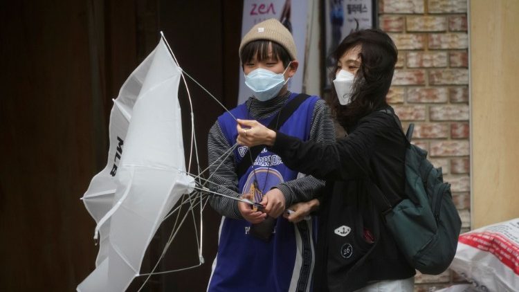 A woman and her child wearing masks to avoid the spread of the coronavirus disease (COVID-19), struggle against strong wind and rain in central Seoul