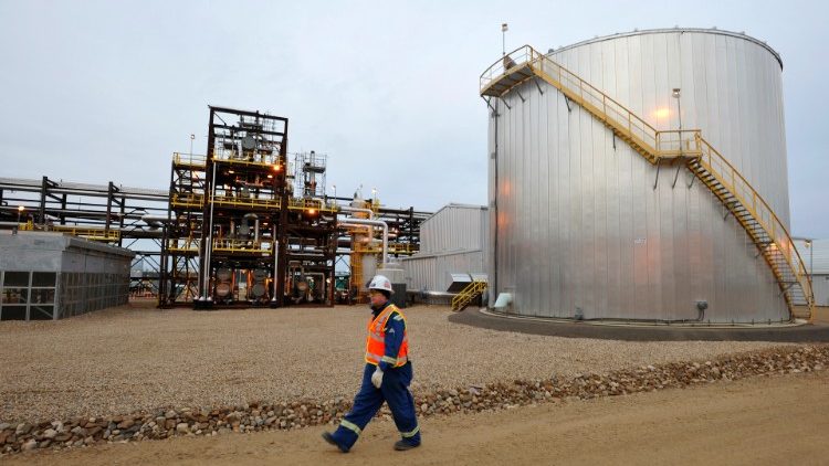 FILE PHOTO: An oilfield worker walks past an oil sands facility