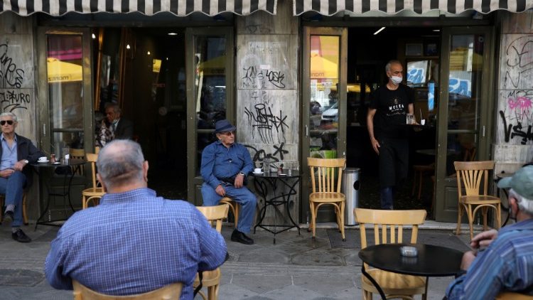 A waiter wearing a masks serves customers in a coffee shop as restaurants reopen, Greece