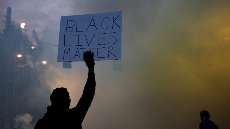 Manifestantes contra la muerte de George Floyd con una pancarta que dice: "La vida de los negros importa".