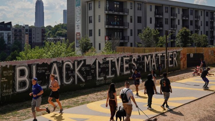 People pass a plywood wall with the 'Black Lives Matter' slogan on it, in Atlanta