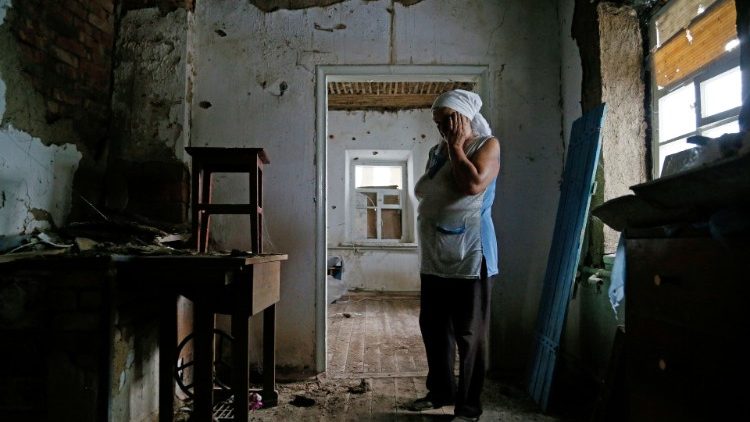 Local resident Katerina Izvekova shows her house damaged during a military conflict in Vesele