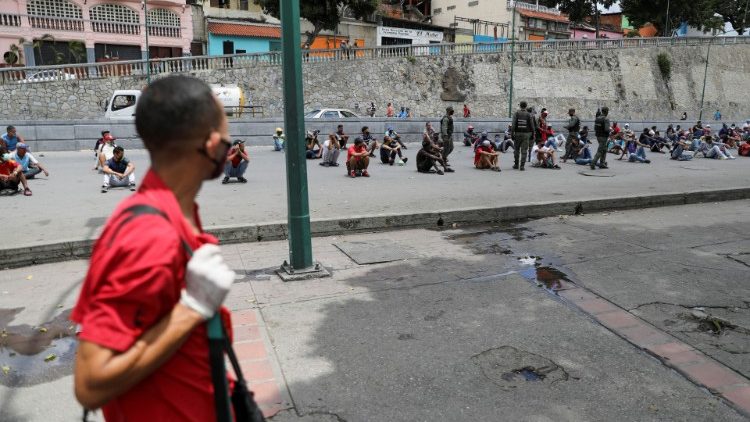 Un hombre observa cómo las fuerzas de seguridad colocan a la gente en medio de la calle como castigo por no respetar el distanciamiento social