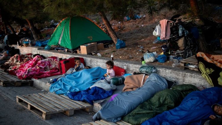 FILE PHOTO: Two children eat cookies as refugees and migrants from the destroyed Moria camp sleep on the side of a road, on the island of Lesbos