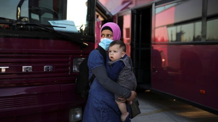 A woman holds a child as refugees and migrants wait to be transferred to camps on the mainland after their arrival on a passenger ferry from the island of Lesbos at the port of Lavrio