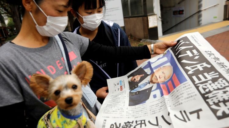 Pessoas lendo jornal em Tóquio sobre as eleições presidenciais nos EUA