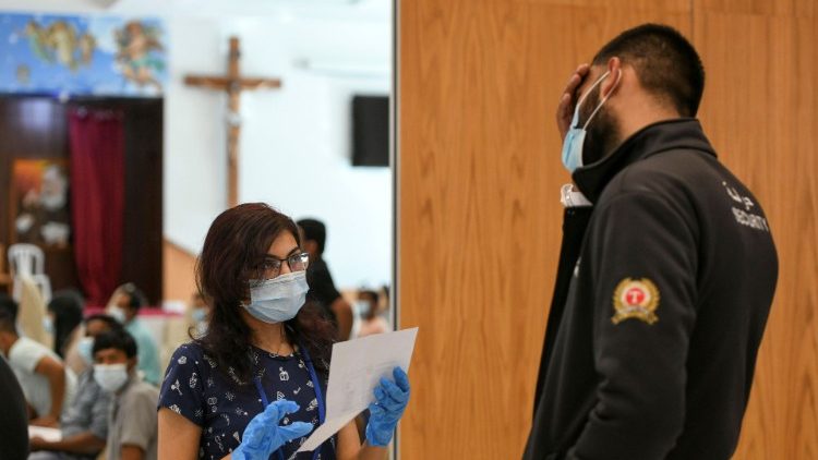 Profissional de saúde conversa pessoa prestes a receber uma dose de uma vacina contra o coronavírus na Igreja de São Paulo,  Abu Dhabi