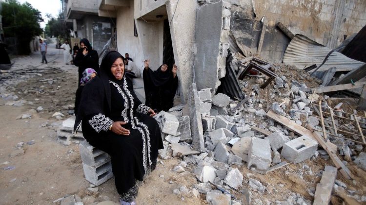 Palestinian women next to the rubble of a home in southern Gaza after alleged Israeli air-strikes in July 2014 