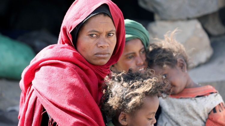 Una mujer yemení con sus hijos esperando la ayuda alimentaria