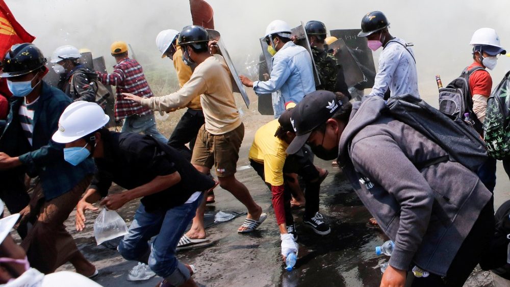 FILE PHOTO: Tear gas and fire extinguisher gas float around demonstrators as they run away from police during a protest against the military coup in Naypyitaw