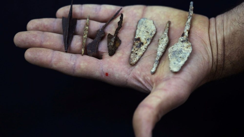 An employee holds ancient arrow and spear heads, part of various artefacts recently discovered in the Judean Desert caves along with scroll fragments of an ancient biblical texts, during an event at Israel Antiquities Authority laboratories in Jerusalem
