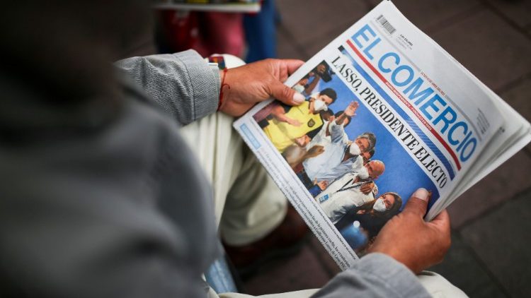 A person holds a newspaper with pictures of presidential candidate Guillermo Lasso, the winner of the presidential election, in Quito