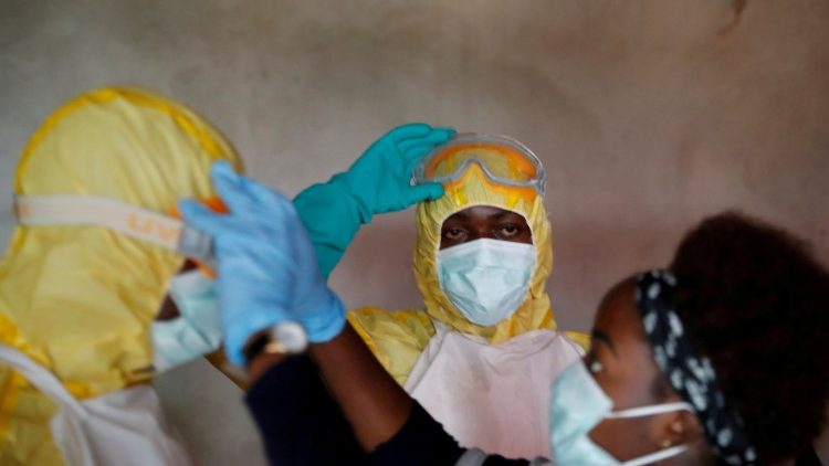 Mitarbeiter des Gesundheitswesens passen ihre Ausrüstung während der Beerdigung einer Person an, bei der der Verdacht besteht, dass sie an Ebola gestorben ist, in Beni.