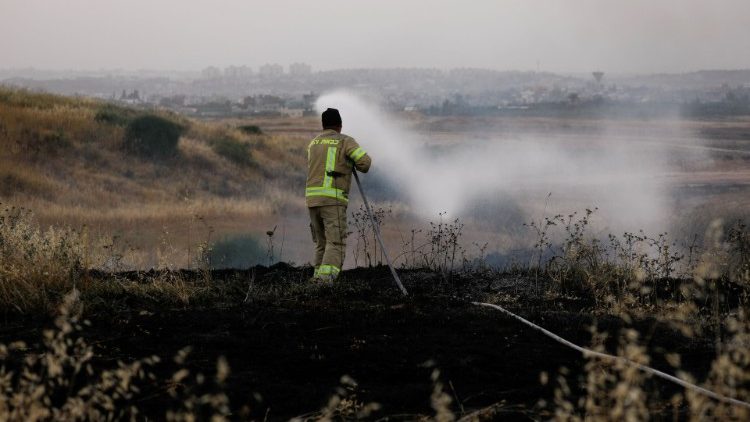 Izraelský hasič hasí pole úmyslně zapálené během posledních střetů