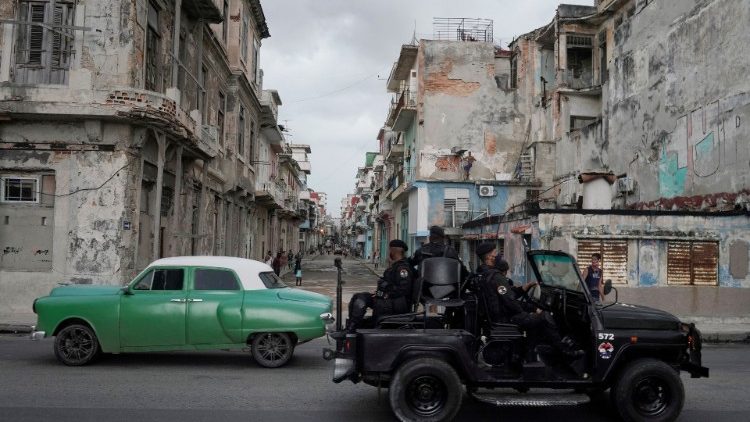 Um veículo das forças de segurança passa por um carro antigo no centro de Havana