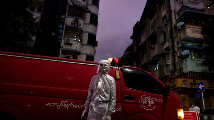 Membro de equipe médica vestindo uma roupa de proteção ao lado de uma ambulância, em meio ao surto da doença do coronavírus (COVID-19), em Yangon.