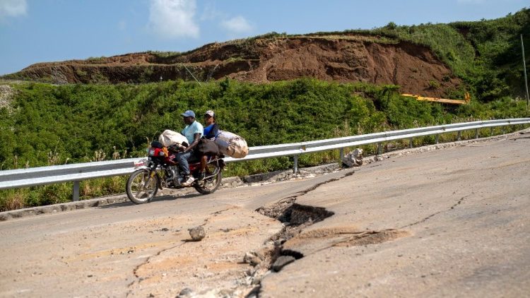 Deux passagers à moto circulent sur une route fissurée par le séisme près des Cayes, en Haïti, le 22 août 2021.