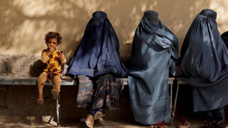 A girl sits with women outside a hospital in Kabul