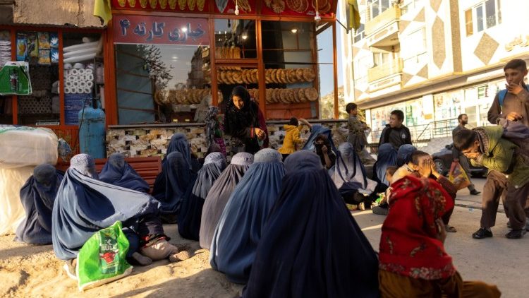 Women are seen lined up outside of a bakery shop in Kabul