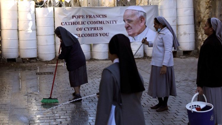 Nuns clean the road in front of the Holy Cross Catholic Church in Nicosia as they prepare to receive Pope Francis