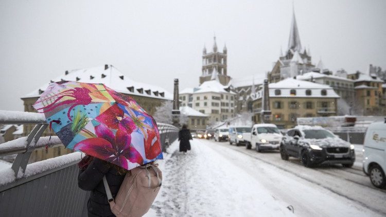 Eine Frau fotografiert bei Schneefall vor der Kathedrale in Lausanne