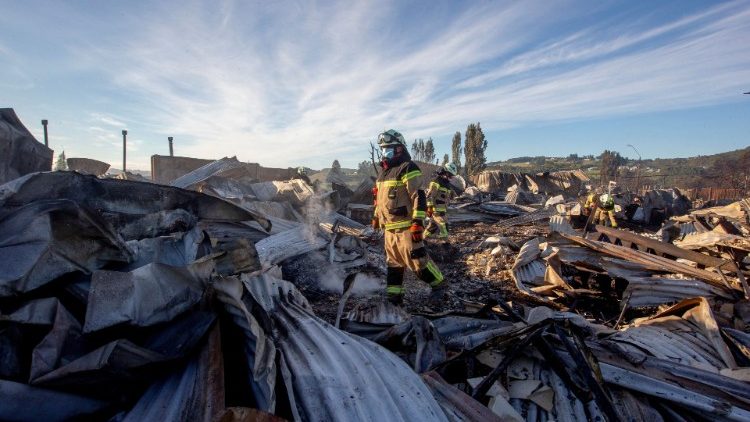 Un bombero camina entre restos de viviendas en zona de Castro, en Chiloé