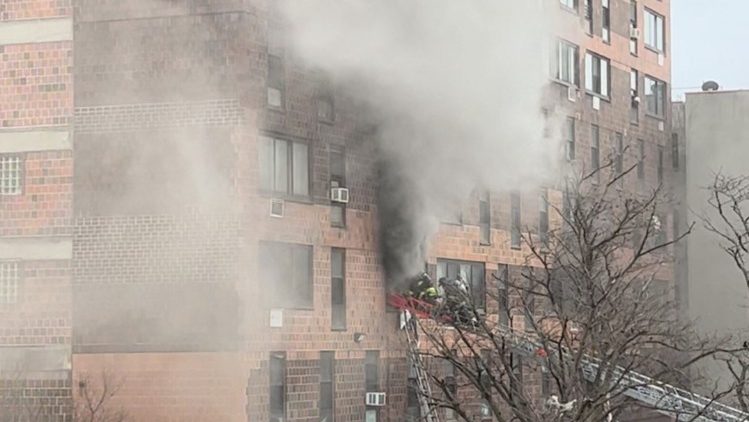 Smoke billows out of the apartment building
